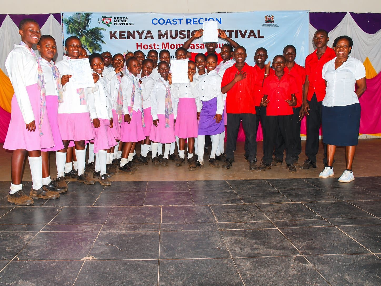 Choir members holding their festival certificates on stage